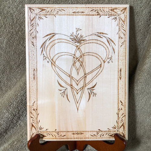 Wood plaque with an interlace heart design on a stand
