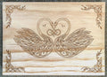 Wooden plaque with intricate Celtic knot design of two swans forming a heart shape.