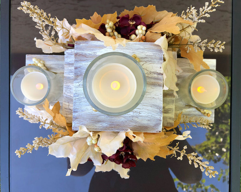Festive three-tiered wooden candleholder with faux autumn flowers and leaves