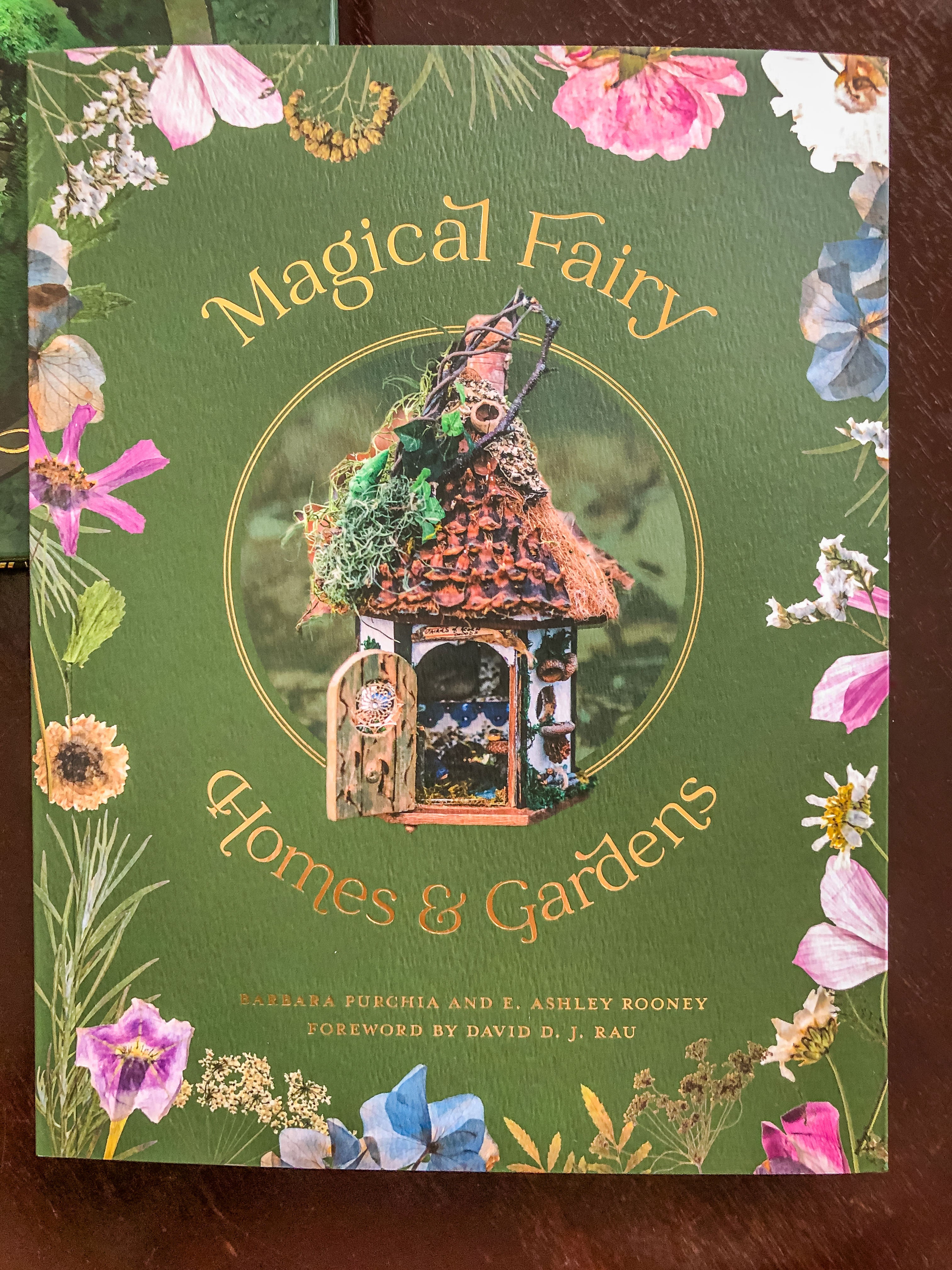 Book cover featuring a fairy house with a floral border