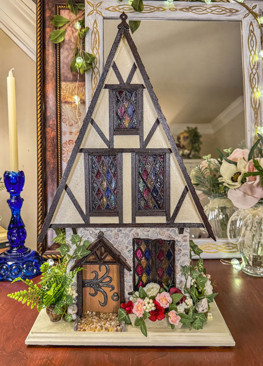 Miniature half timber house with stained glass windows on a table