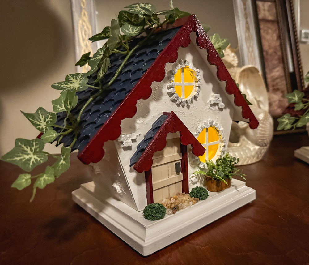 Miniature red white and blue cottage with scalloped roof trim on a table