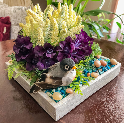 Candleholder with faux white and purple flowers and a mini bird on a table
