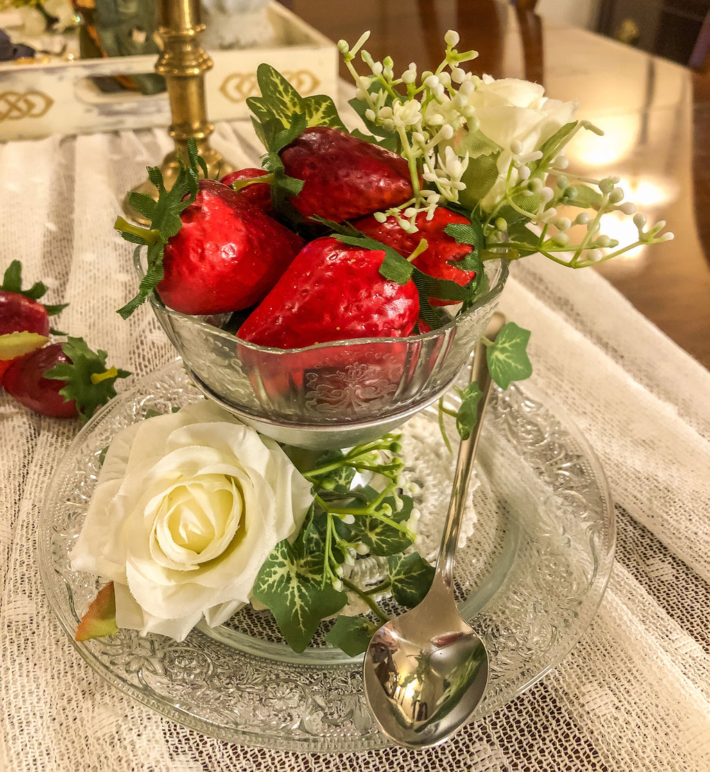 Artificial strawberries with white roses and  ivy in a dessert cup on a glass plate