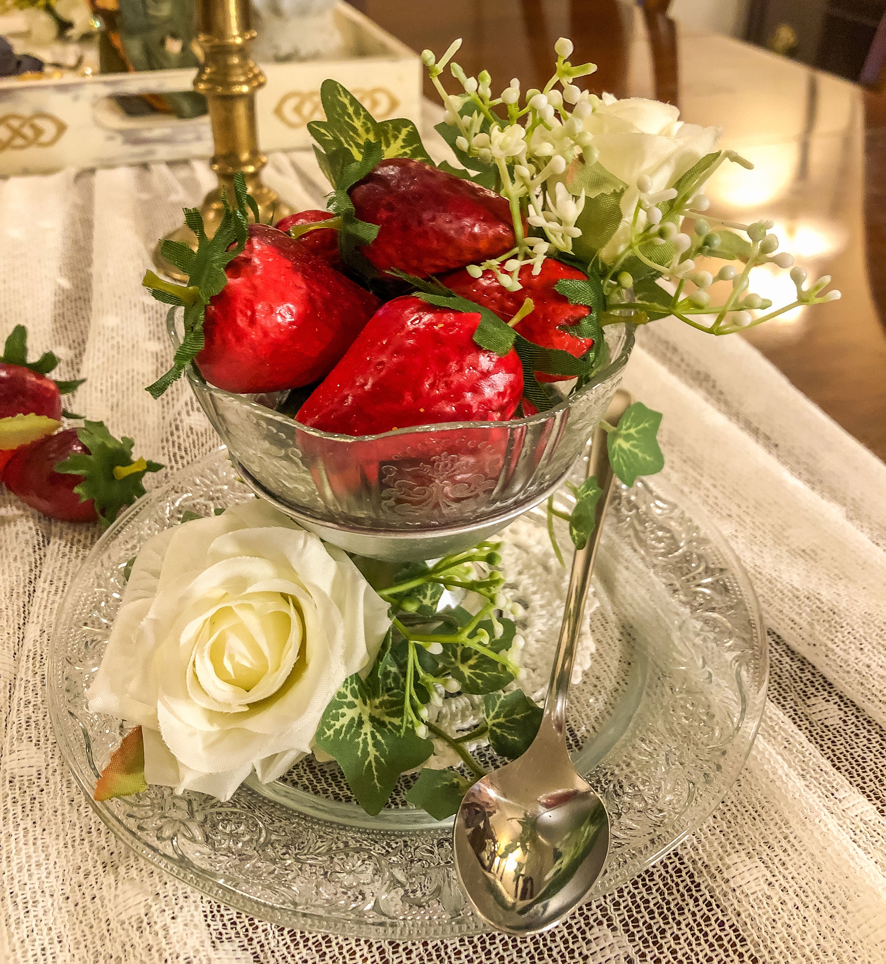 Artificial strawberries with white roses and  ivy in a dessert cup on a glass plate