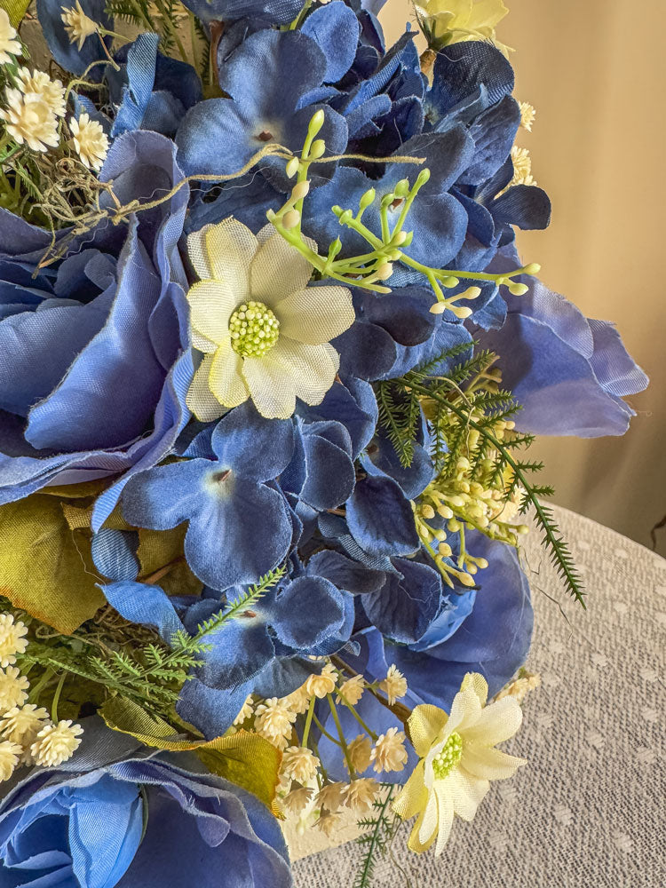 Wood candleholder with blue fabric rose and hydrangea arrangement