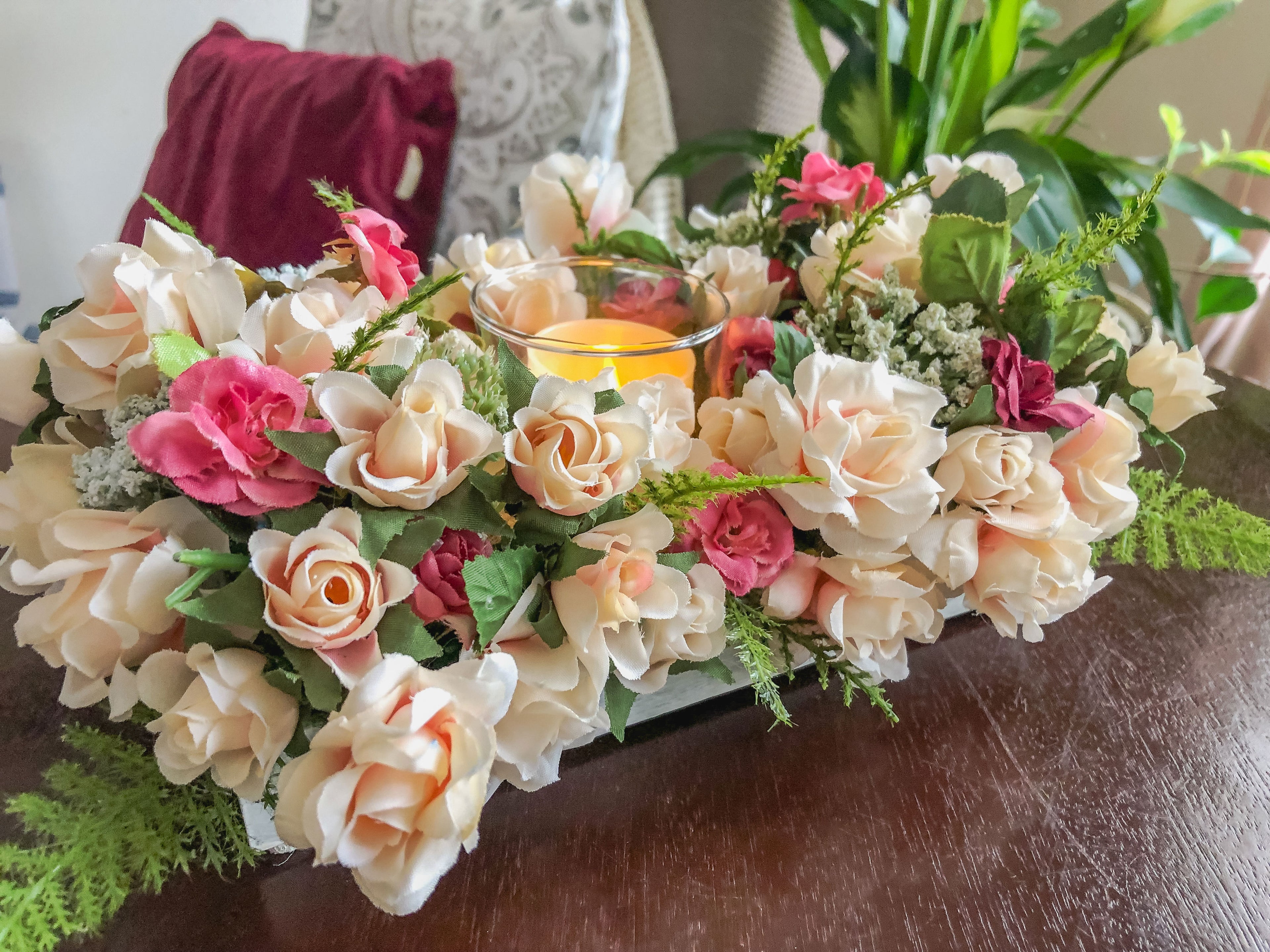 Candleholder with faux miniature pink and coral roses in a tray on a table