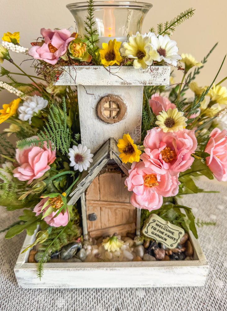 Wood candleholder with a miniature fairy tower in a flower bush