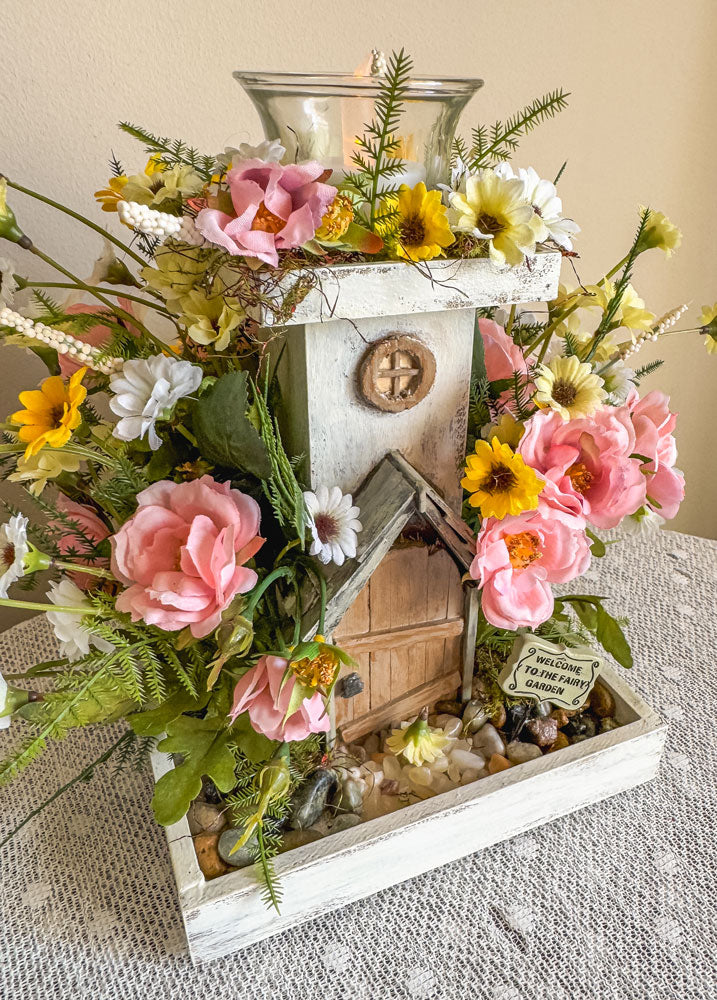 Wood candleholder with a miniature fairy tower in a flower bush