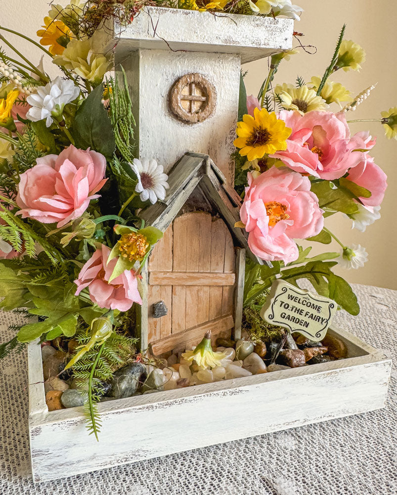 Wood candleholder with a miniature fairy tower in a flower bush
