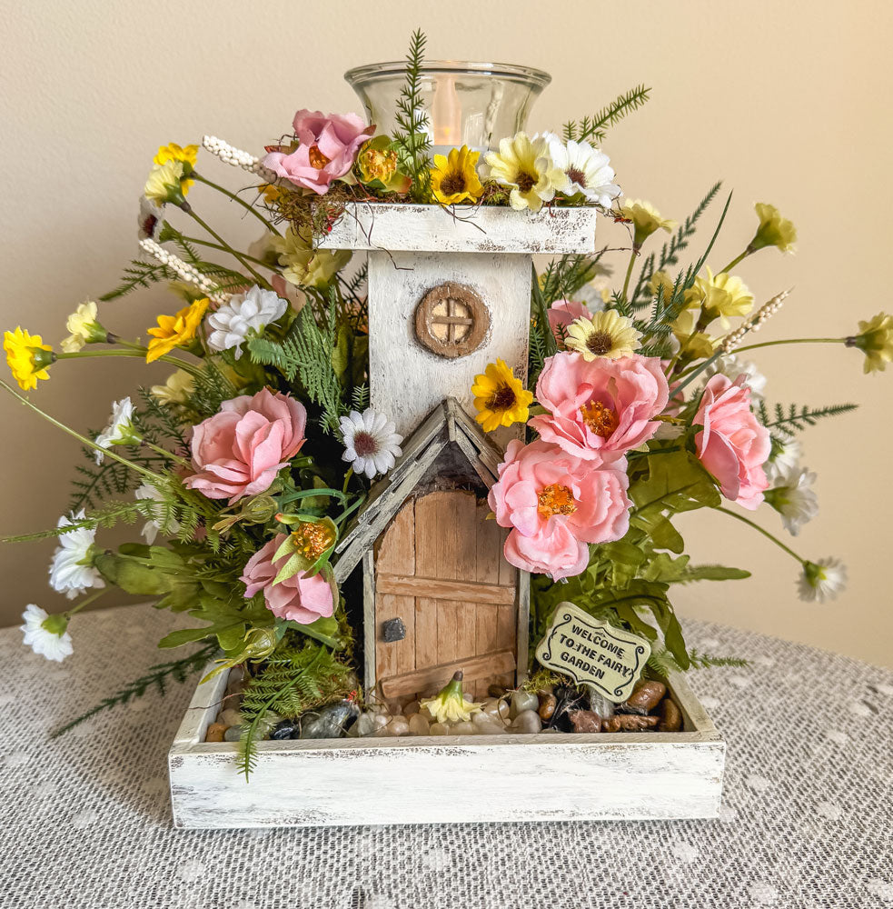 Wood candleholder with a miniature fairy tower in a flower bush