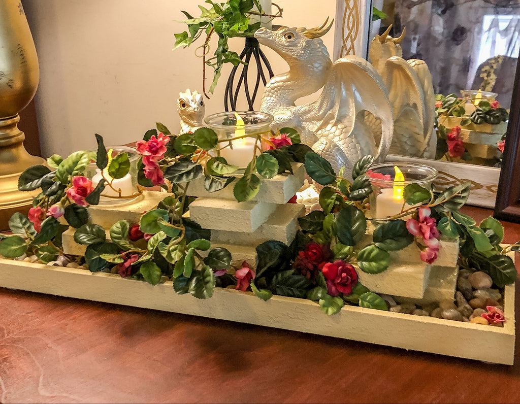 Garden themed candleholder with miniature faux roses on a table with a dragon