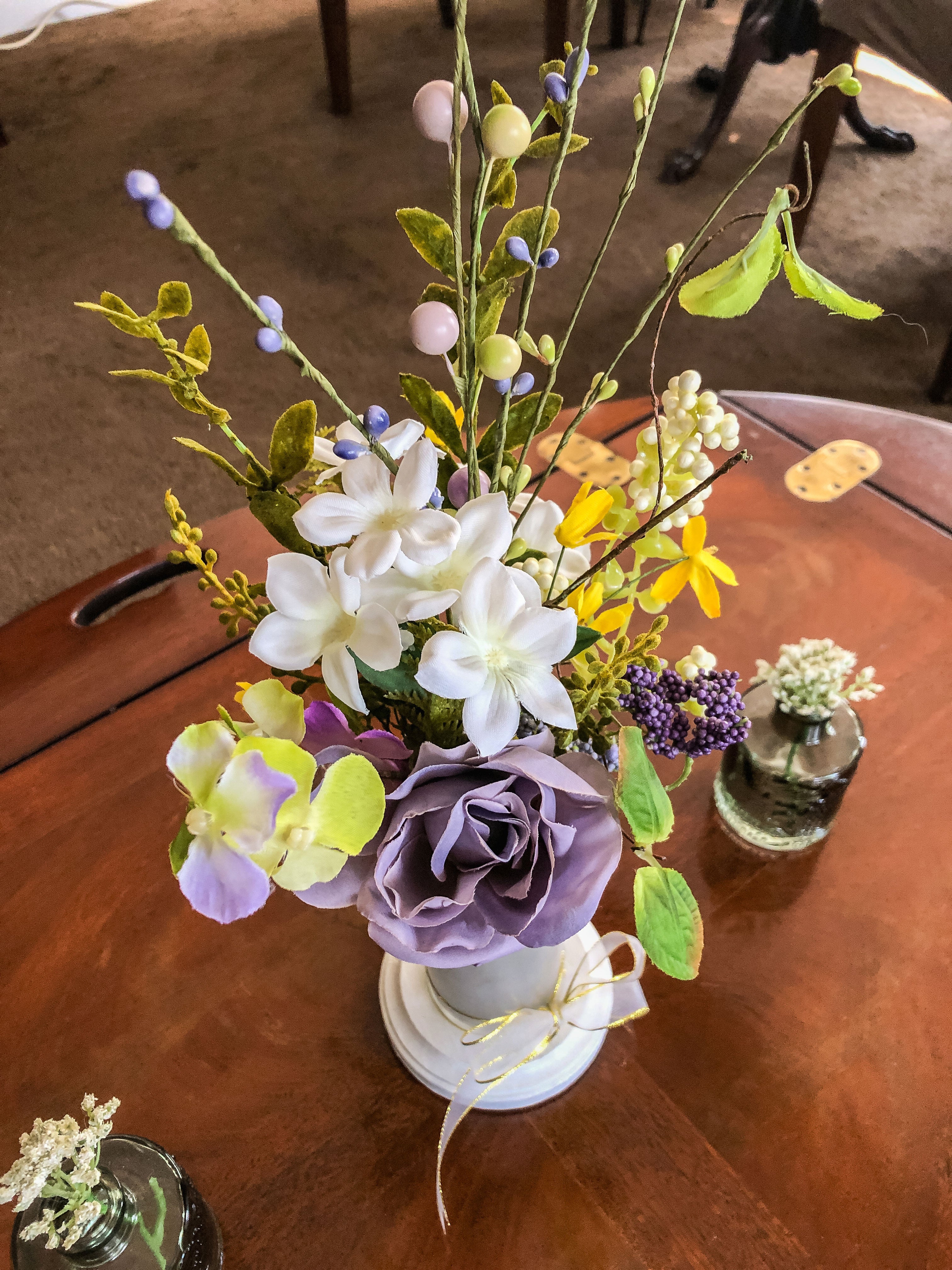 Purple fabric rose flower arrangement in a frosted glass