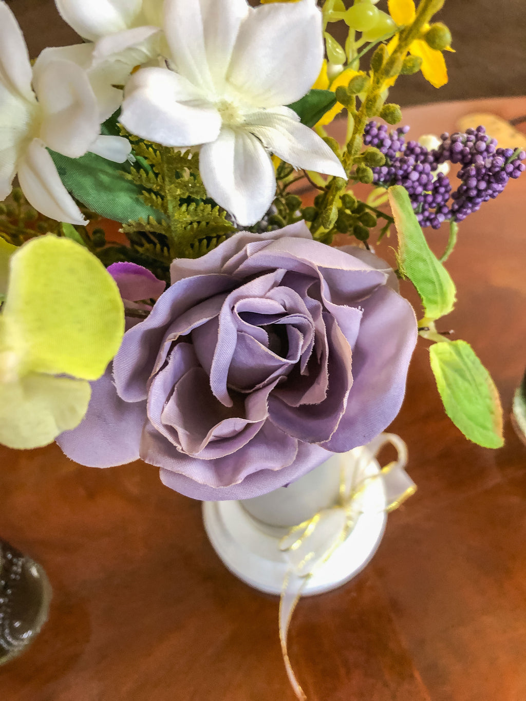 Purple fabric rose flower arrangement in a frosted glass