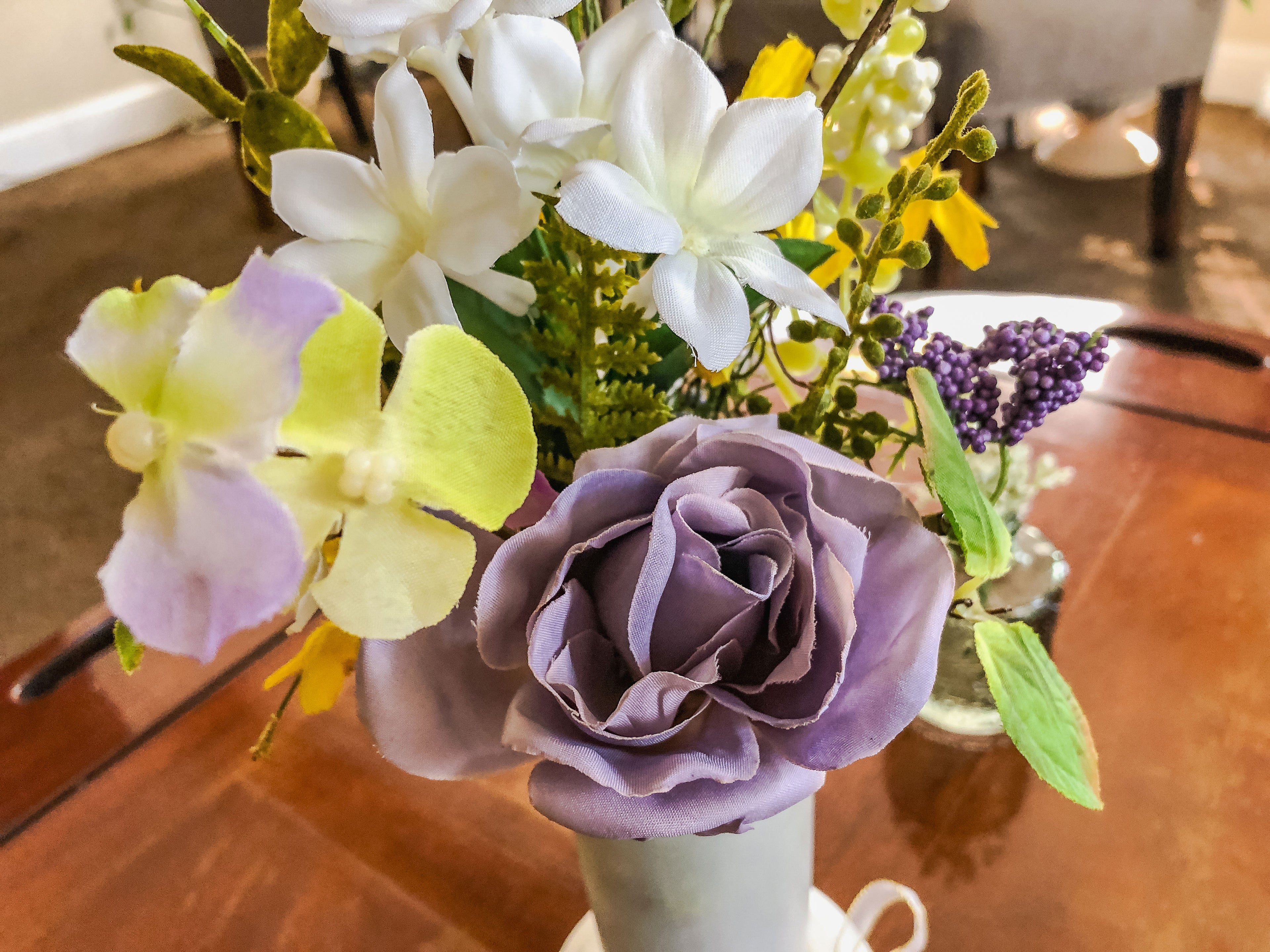 Purple fabric rose flower arrangement in a frosted glass