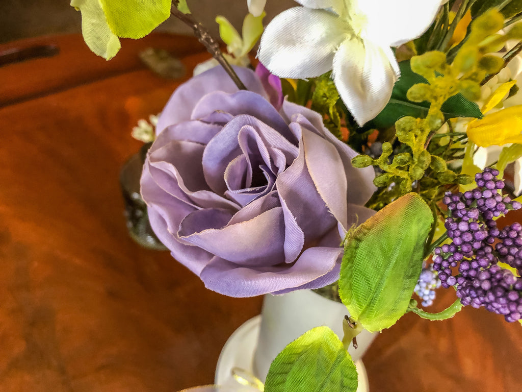 Purple fabric rose flower arrangement in a frosted glass