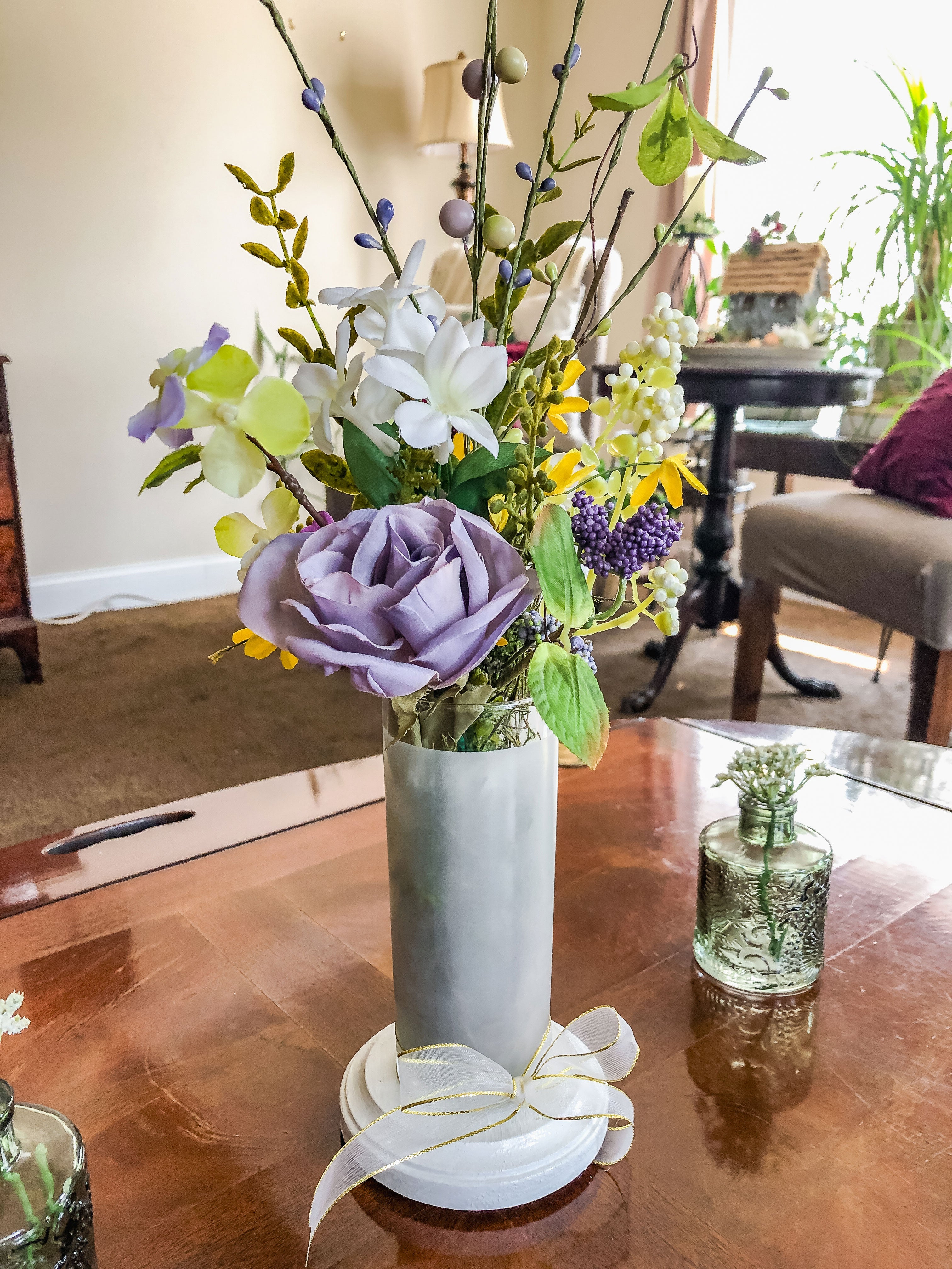 Purple fabric rose flower arrangement in a frosted glass