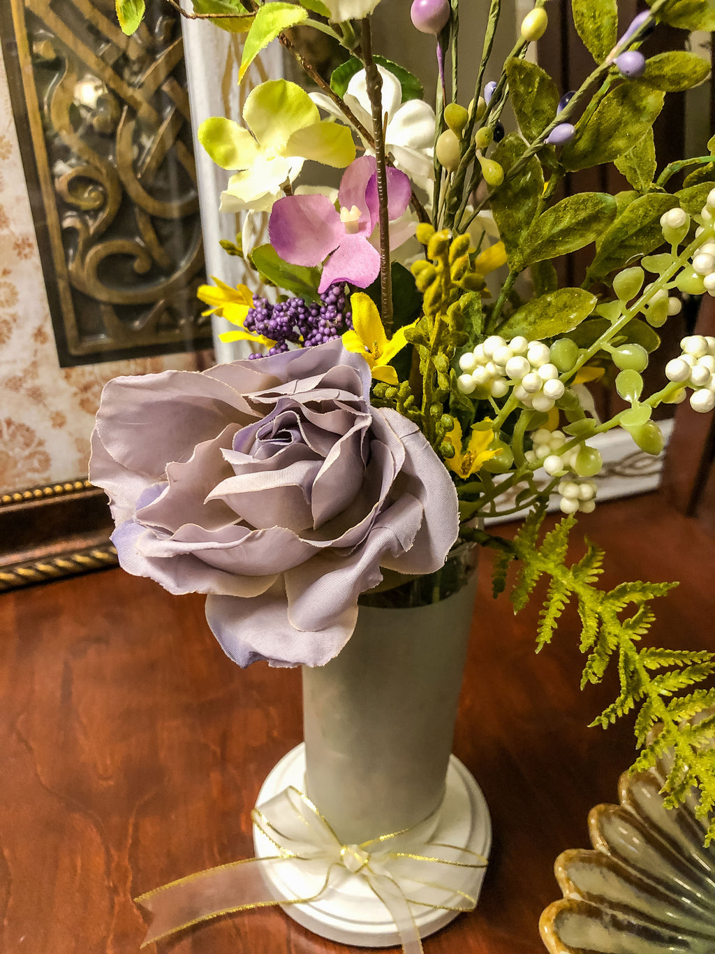 Faux floral arrangement with a purple rose in a frosted glass with a ribbon