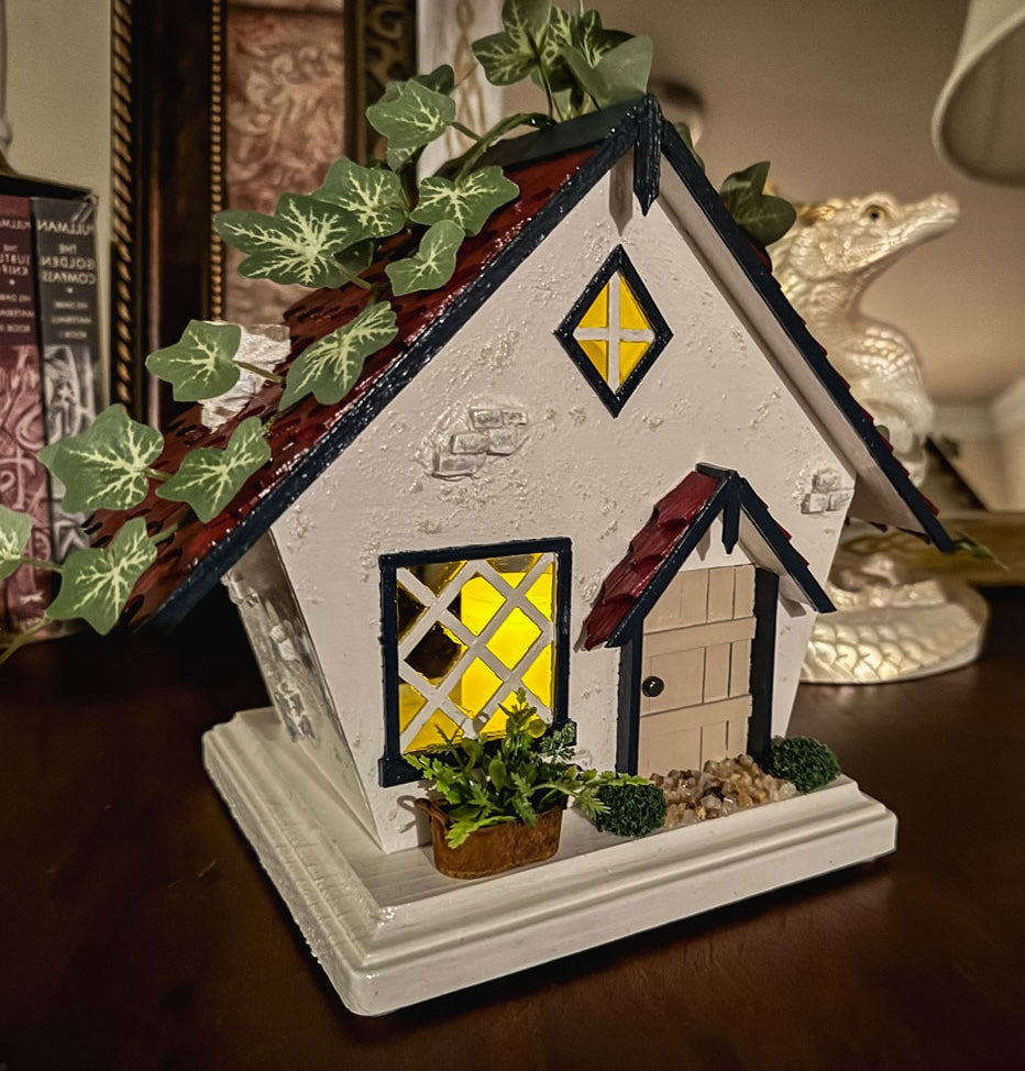 Miniature red white and blue cottage with faux ivy on a table