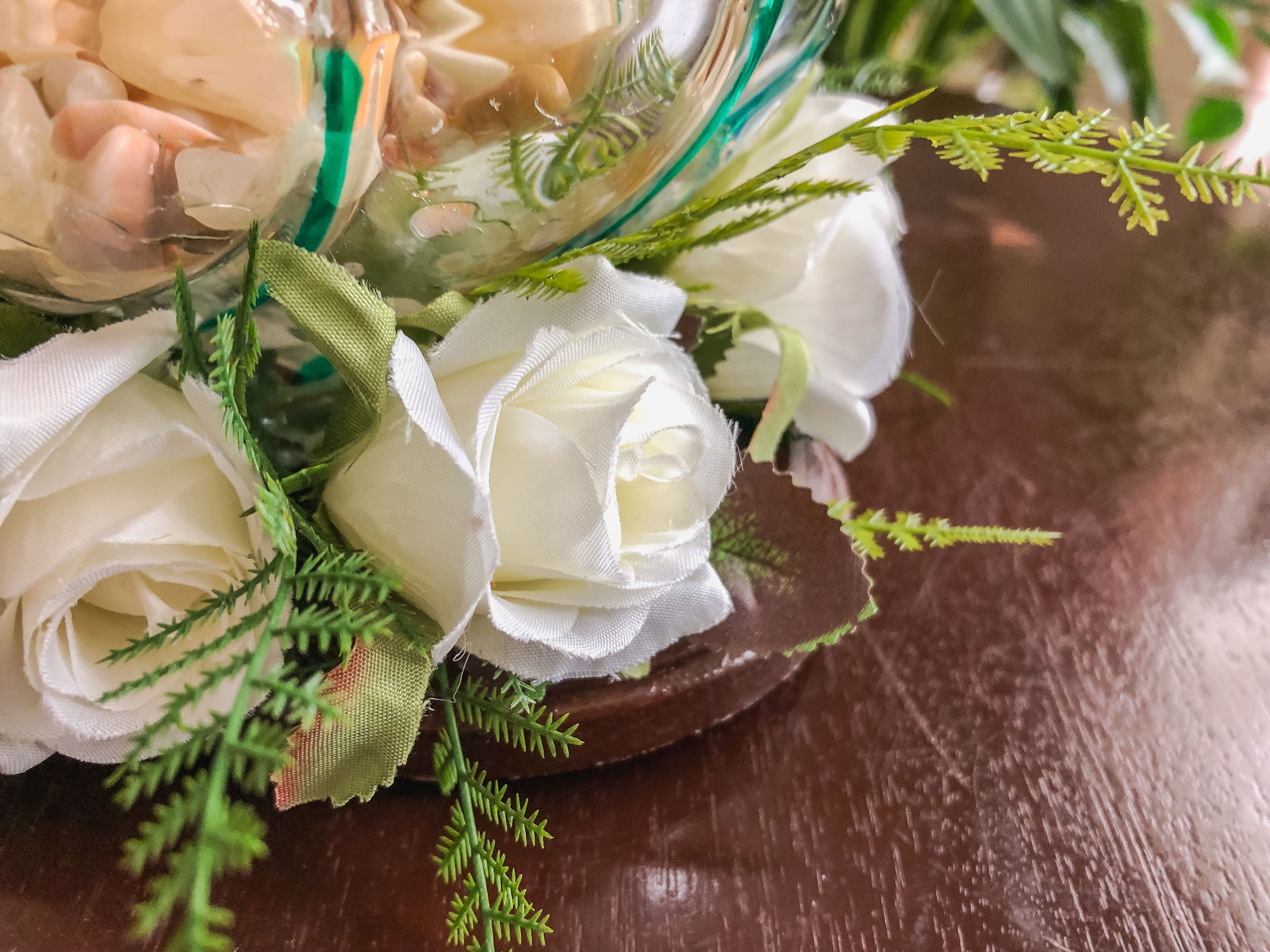 Votive candleholder with a striped glass bowl ringed with white roses