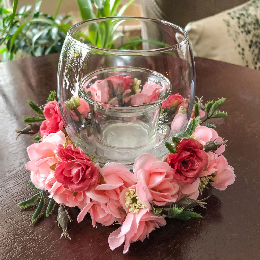 Votive candle holder with faux pink floral ring on a table