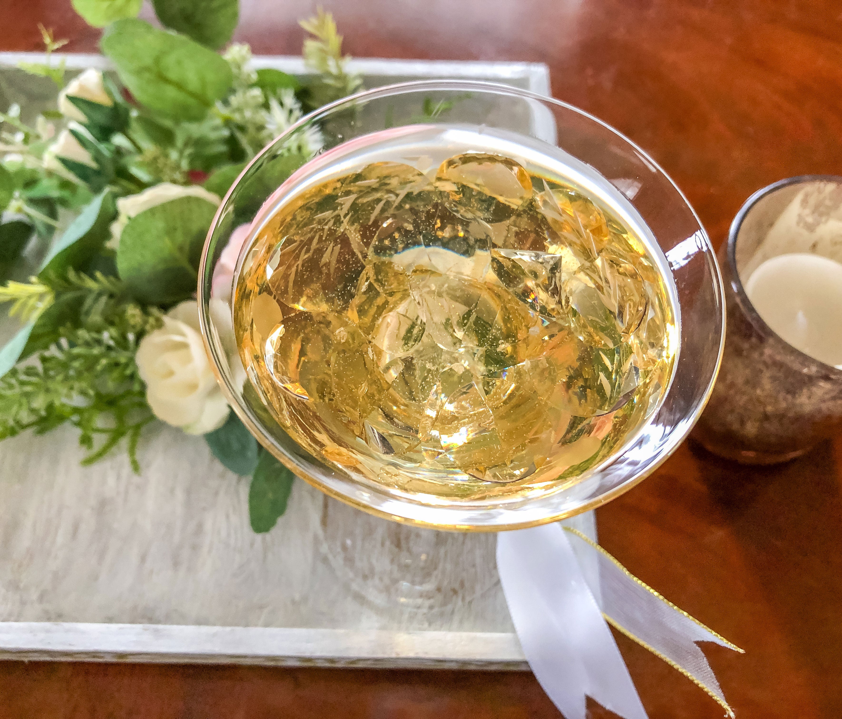Wedding-inspired faux floral display with up-cycled champagne glass in a tray