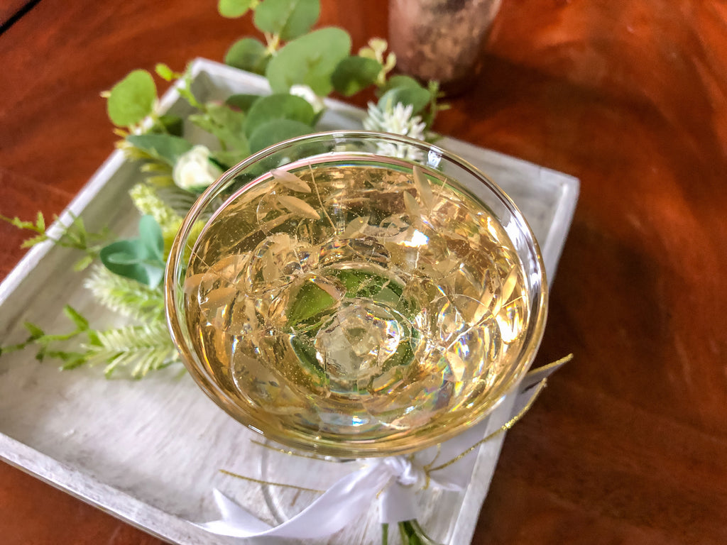 Wedding-inspired faux floral display with up-cycled champagne glass in a tray