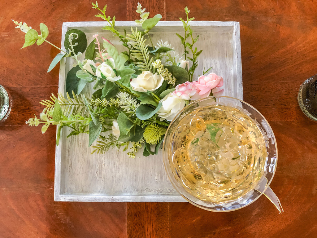 Wedding-inspired faux floral display with up-cycled champagne glass in a tray