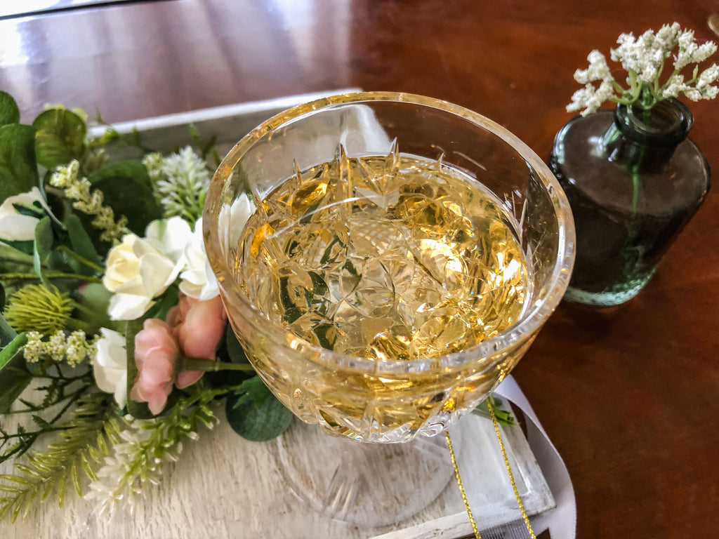 Wedding-inspired faux floral display with up-cycled champagne glass in a tray