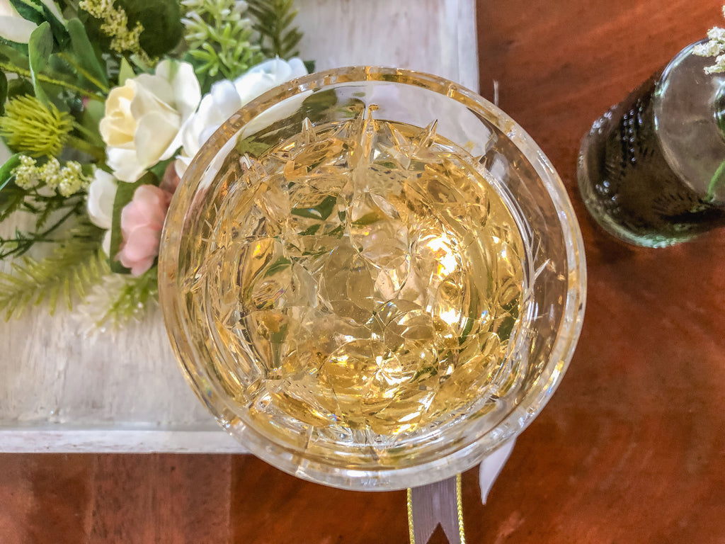 Wedding-inspired faux floral display with up-cycled champagne glass in a tray