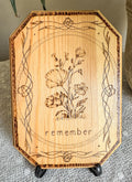 Small wood plaque with poppies and the word remember on a stand
