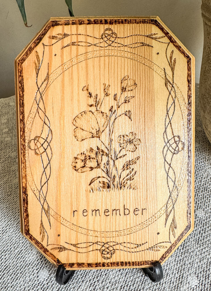 Small wood plaque with poppies and the word remember on a stand